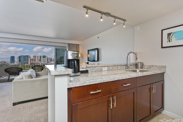 kitchen featuring kitchen peninsula, sink, and light stone counters