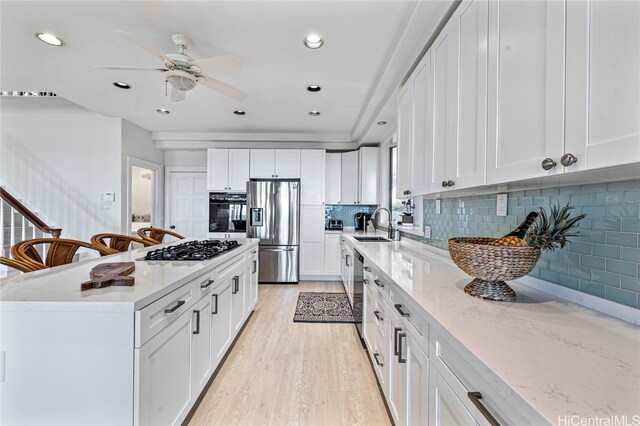 kitchen with decorative backsplash, sink, white cabinetry, appliances with stainless steel finishes, and light hardwood / wood-style floors