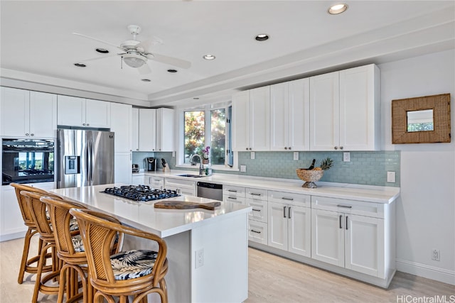 kitchen featuring white cabinetry, appliances with stainless steel finishes, light wood-type flooring, and a kitchen bar