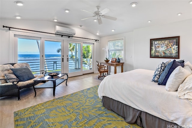 bedroom with a wall mounted AC, access to exterior, vaulted ceiling, a water view, and light hardwood / wood-style floors