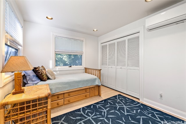 bedroom featuring a wall unit AC, hardwood / wood-style floors, and a closet