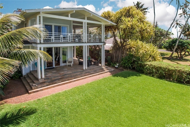 rear view of house with a patio area, a lawn, and a balcony