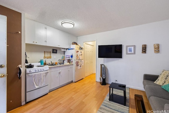 kitchen featuring sink, light hardwood / wood-style floors, a textured ceiling, white appliances, and white cabinets