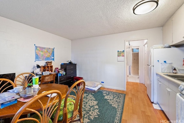 dining area with a textured ceiling and light hardwood / wood-style floors