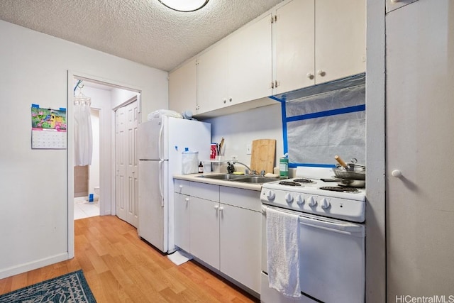 kitchen featuring white appliances, sink, a textured ceiling, light hardwood / wood-style floors, and white cabinetry