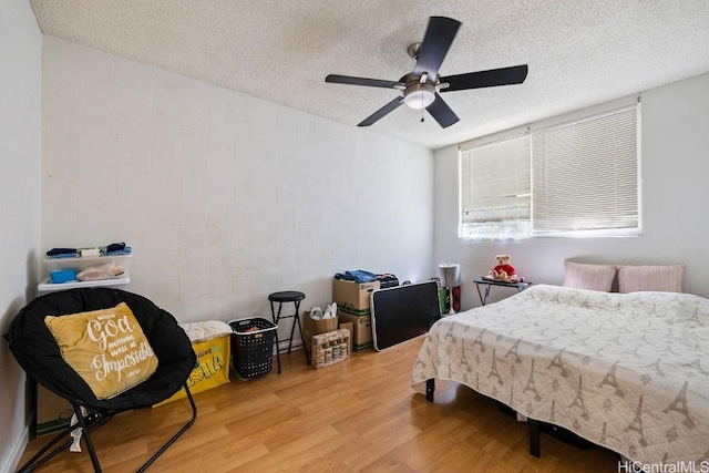 bedroom with ceiling fan, hardwood / wood-style floors, and a textured ceiling