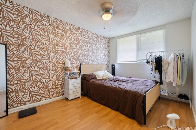 bedroom with a textured ceiling, light hardwood / wood-style floors, and ceiling fan