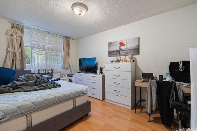 bedroom with a textured ceiling and light hardwood / wood-style floors