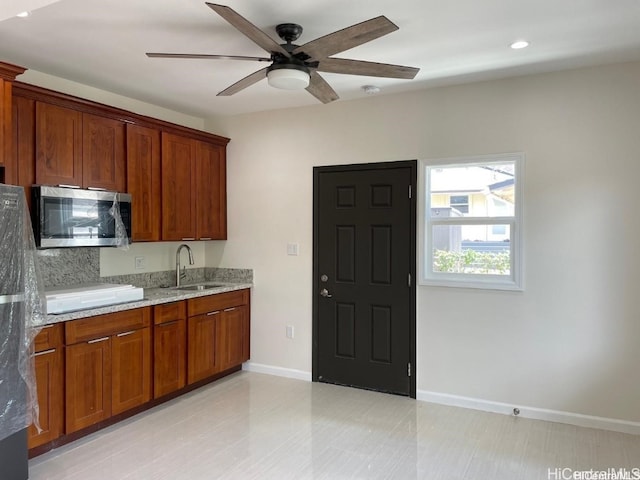 kitchen featuring tasteful backsplash, light tile patterned floors, ceiling fan, light stone countertops, and sink