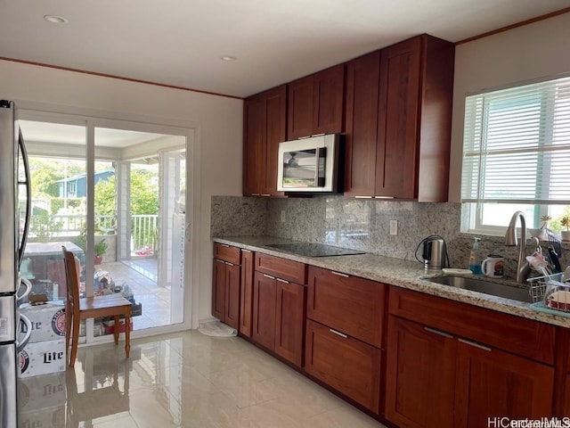 kitchen with sink, light stone countertops, and a healthy amount of sunlight