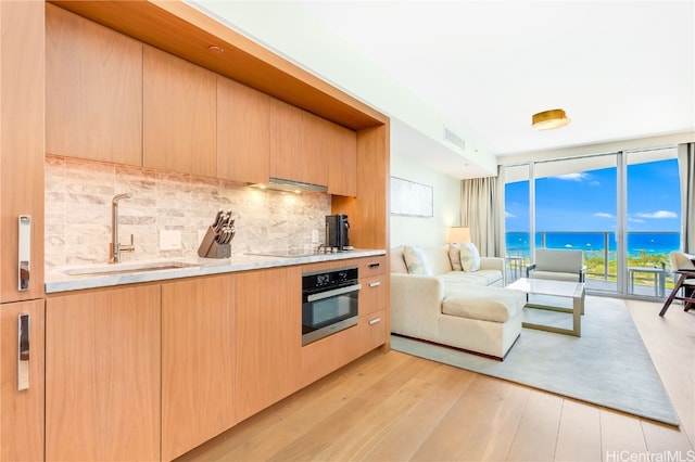 kitchen featuring sink, a water view, light wood-type flooring, and oven