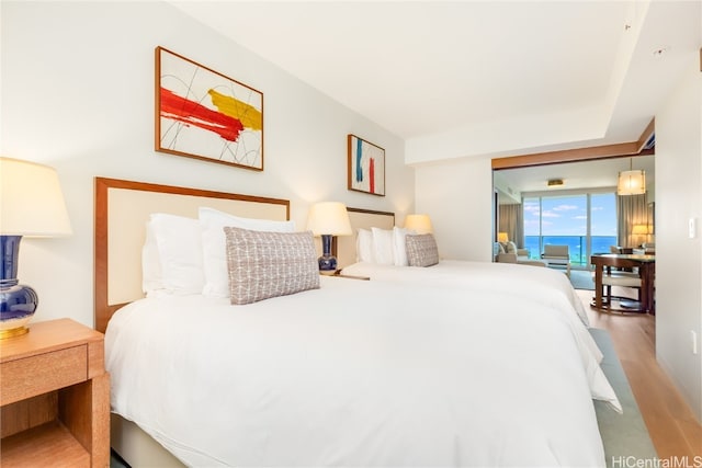 bedroom with a water view and hardwood / wood-style flooring