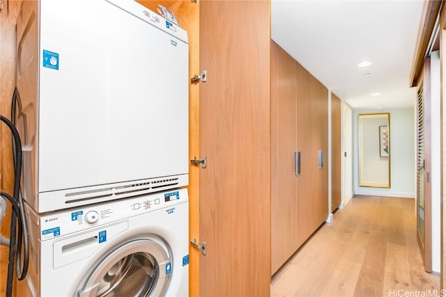 washroom with light hardwood / wood-style flooring and stacked washer / drying machine