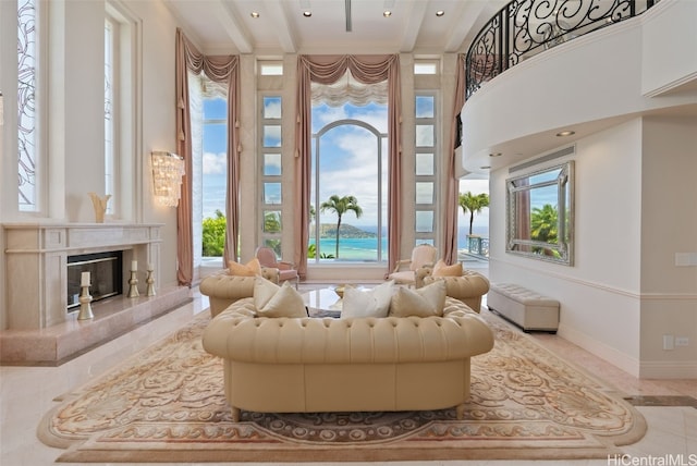 sitting room with a towering ceiling, light tile patterned flooring, a high end fireplace, and beamed ceiling