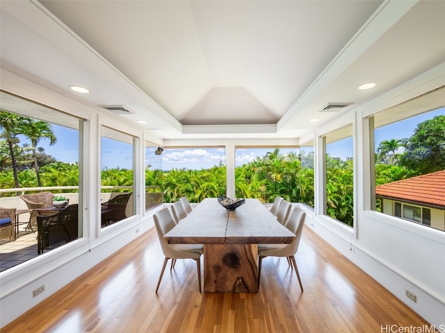 sunroom with lofted ceiling, a raised ceiling, and plenty of natural light