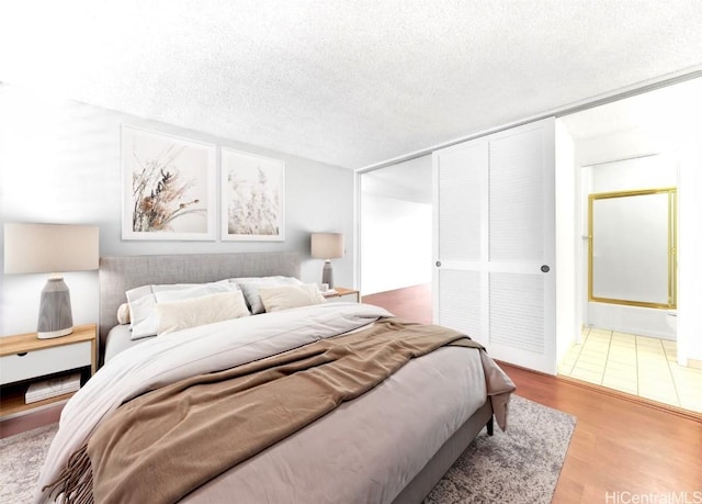 bedroom with a textured ceiling, a closet, and wood finished floors