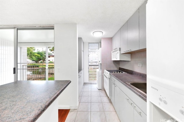 kitchen with tasteful backsplash, a textured ceiling, white appliances, sink, and light tile patterned flooring