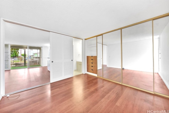 unfurnished bedroom with a textured ceiling, a closet, and wood finished floors