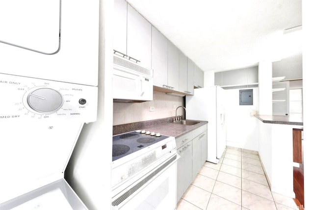 kitchen with dark countertops, stacked washer / dryer, a sink, white appliances, and electric panel