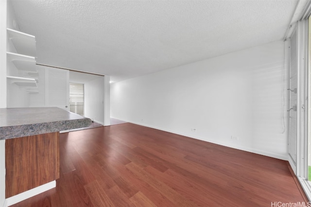 unfurnished living room featuring a textured ceiling and dark wood finished floors