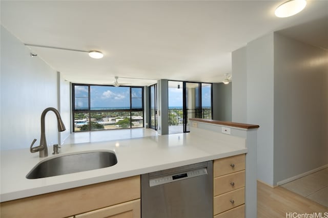 kitchen with light brown cabinetry, stainless steel dishwasher, sink, and light wood-type flooring