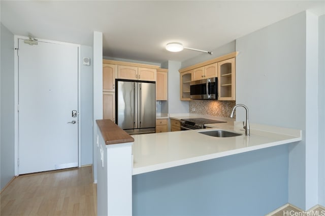 kitchen featuring appliances with stainless steel finishes, kitchen peninsula, sink, and light wood-type flooring