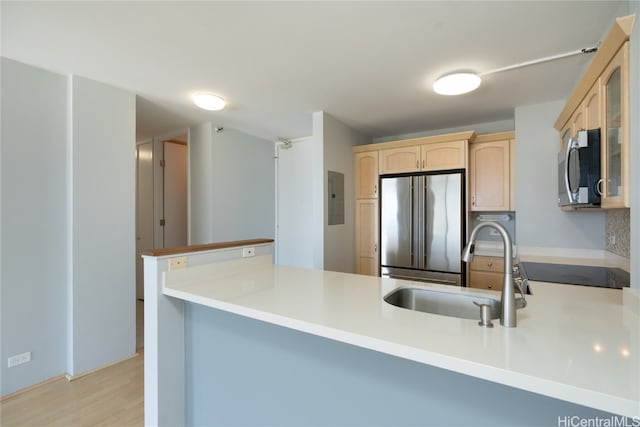 kitchen featuring light brown cabinetry, sink, light wood-type flooring, kitchen peninsula, and stainless steel appliances