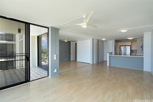 unfurnished living room with sink, light hardwood / wood-style floors, and ceiling fan