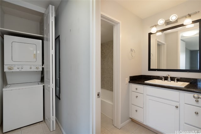 clothes washing area featuring light tile patterned floors, sink, and stacked washer and dryer