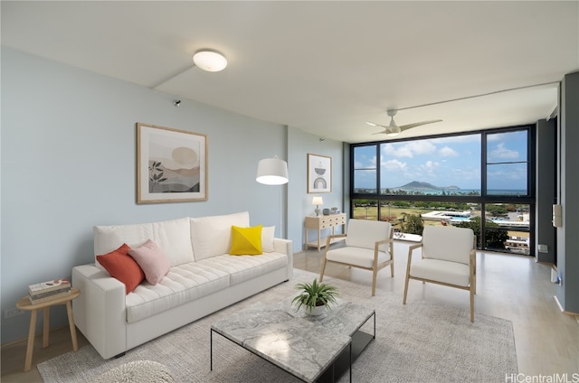 living room with a wall of windows, light wood-type flooring, and ceiling fan