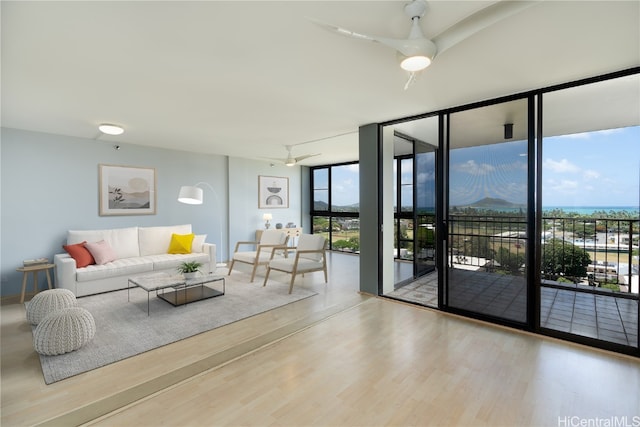 living room with ceiling fan, hardwood / wood-style flooring, and a wall of windows