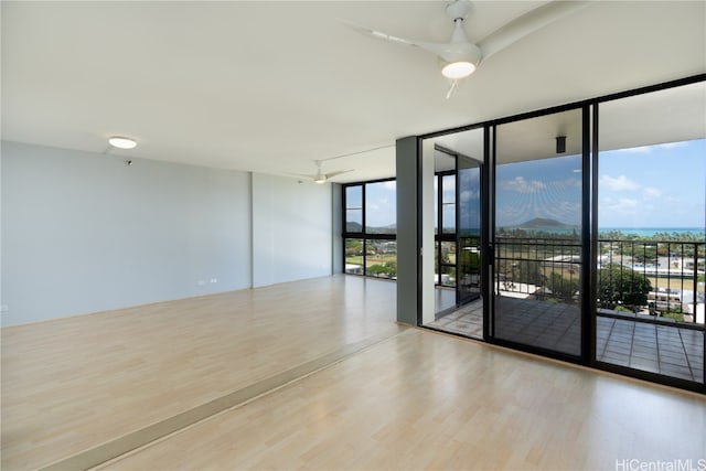 unfurnished room with light hardwood / wood-style flooring, floor to ceiling windows, and ceiling fan