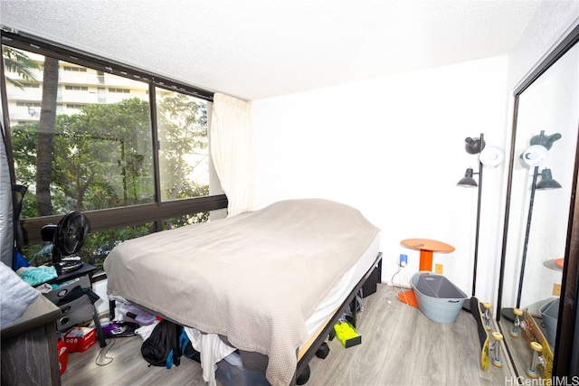 bedroom featuring hardwood / wood-style floors, a textured ceiling, and floor to ceiling windows