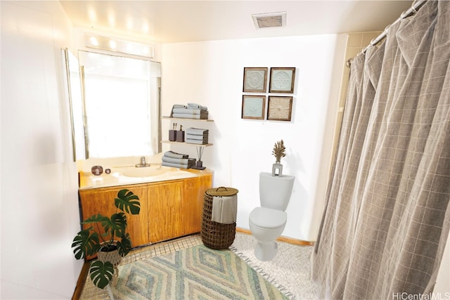 bathroom with toilet, vanity, and tile patterned floors