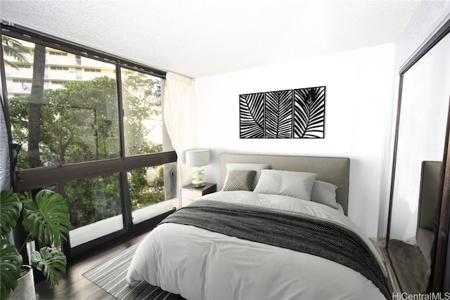 bedroom featuring hardwood / wood-style floors, a textured ceiling, a closet, and expansive windows