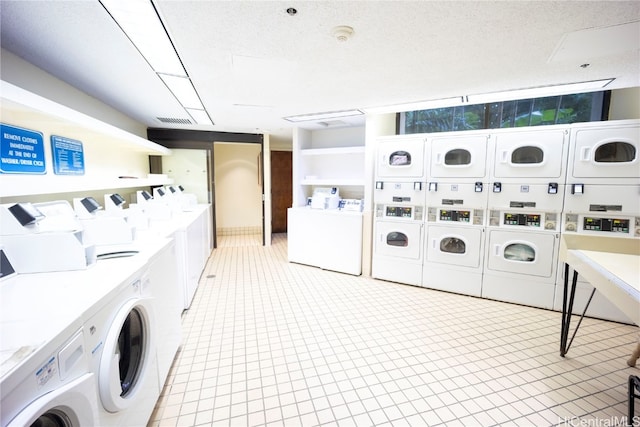 clothes washing area featuring washing machine and dryer, a textured ceiling, and stacked washer and clothes dryer