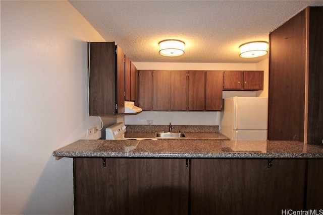 kitchen featuring white appliances, a textured ceiling, kitchen peninsula, dark stone counters, and extractor fan