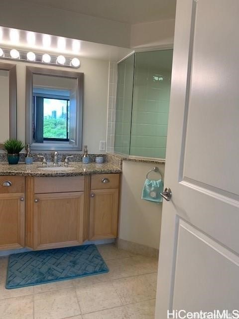 bathroom featuring vanity, a tile shower, and tile patterned flooring