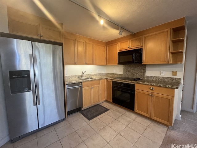 kitchen with dark stone countertops, sink, black appliances, rail lighting, and light tile patterned floors