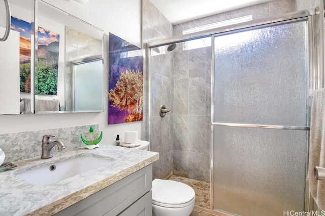 bathroom featuring toilet, vanity, and a shower with door