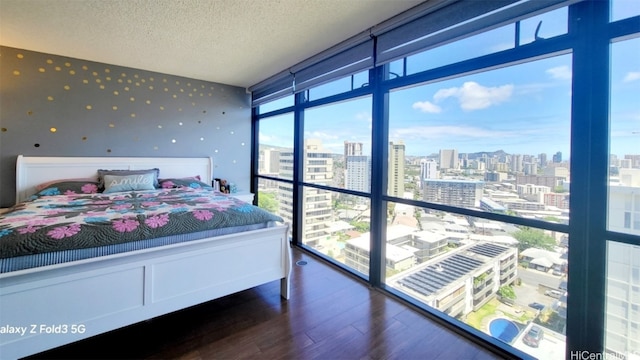 bedroom featuring a textured ceiling, wood-type flooring, multiple windows, and floor to ceiling windows