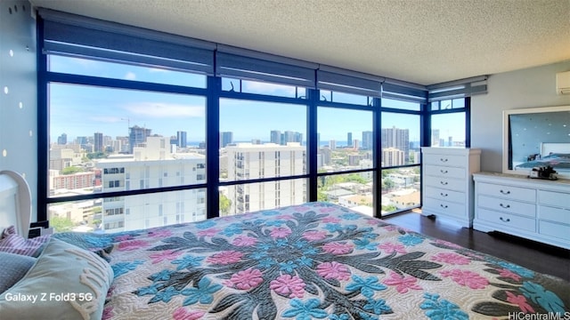 bedroom with an AC wall unit, a textured ceiling, a wall of windows, and dark hardwood / wood-style floors