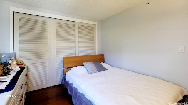 bedroom featuring a closet, a textured ceiling, and dark hardwood / wood-style flooring