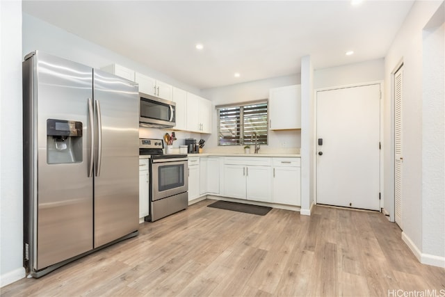 kitchen with white cabinetry, stainless steel appliances, and light hardwood / wood-style floors