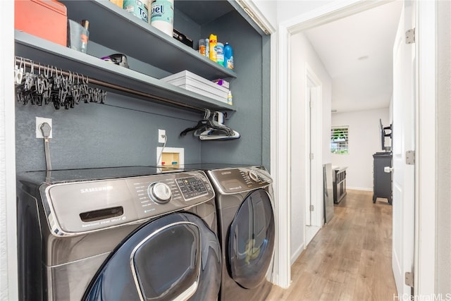 clothes washing area featuring light hardwood / wood-style flooring and washer and clothes dryer