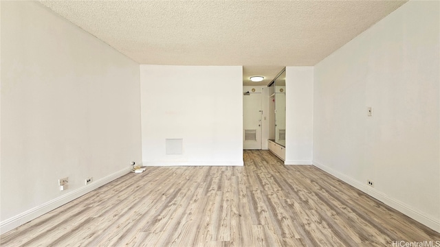 spare room with a textured ceiling and light hardwood / wood-style floors