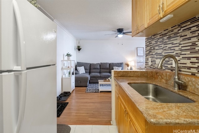 kitchen with tasteful backsplash, sink, a textured ceiling, light hardwood / wood-style flooring, and white refrigerator