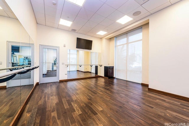 exercise area featuring a towering ceiling, a drop ceiling, and dark wood-type flooring