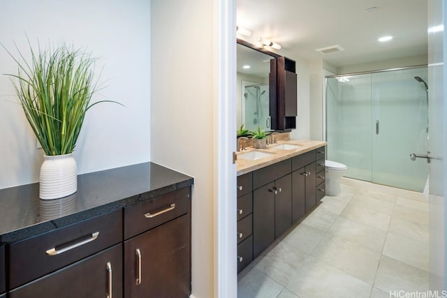 bathroom featuring a shower with door, vanity, toilet, and tile patterned flooring