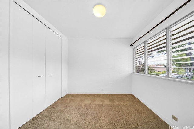 unfurnished bedroom with a closet and light colored carpet